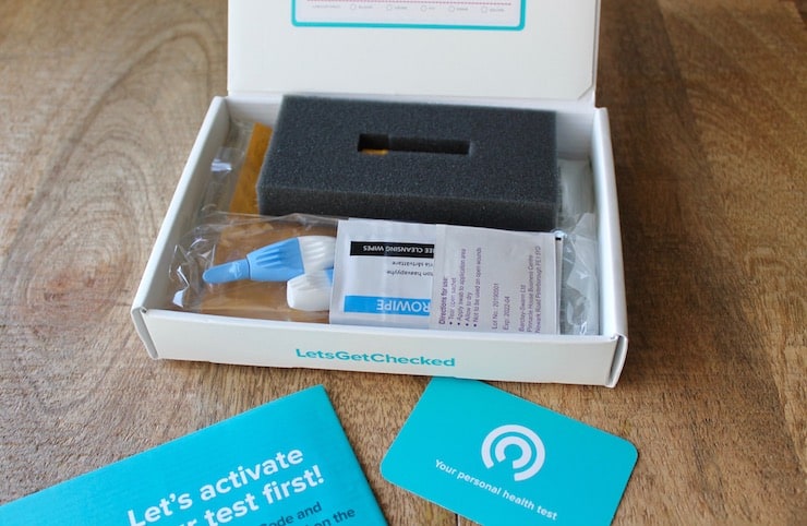 Open white box with vitamin testing supplies inside sitting on wooden table