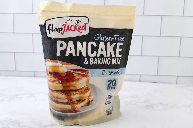 Bag of FlapJacked gluten free pancake mix on white marble surface with white subway tile background