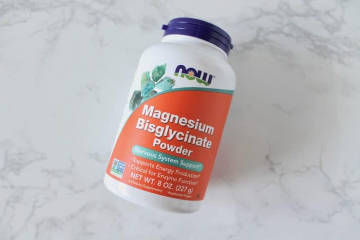 Orange and white supplement bottle of magnesium on a white marble surface