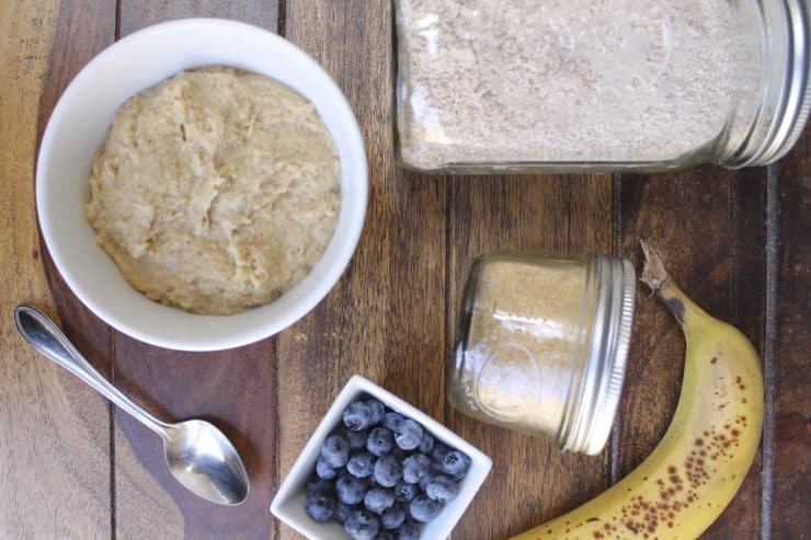 Overhead shot of grain free oat recipe ingredients including banana, blueberries, flax seeds and almond meal next to the bowl of finished oats on a wooden surface