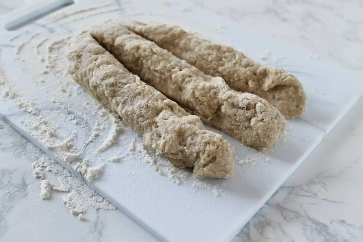 three thick ropes of bread dough in a line on a floured surface