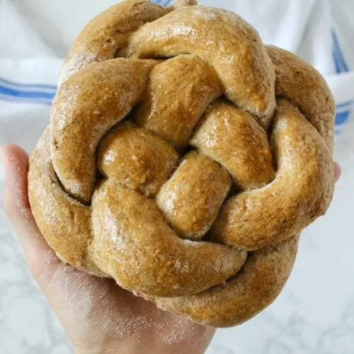 A person is holding a braided gluten free challah bread.