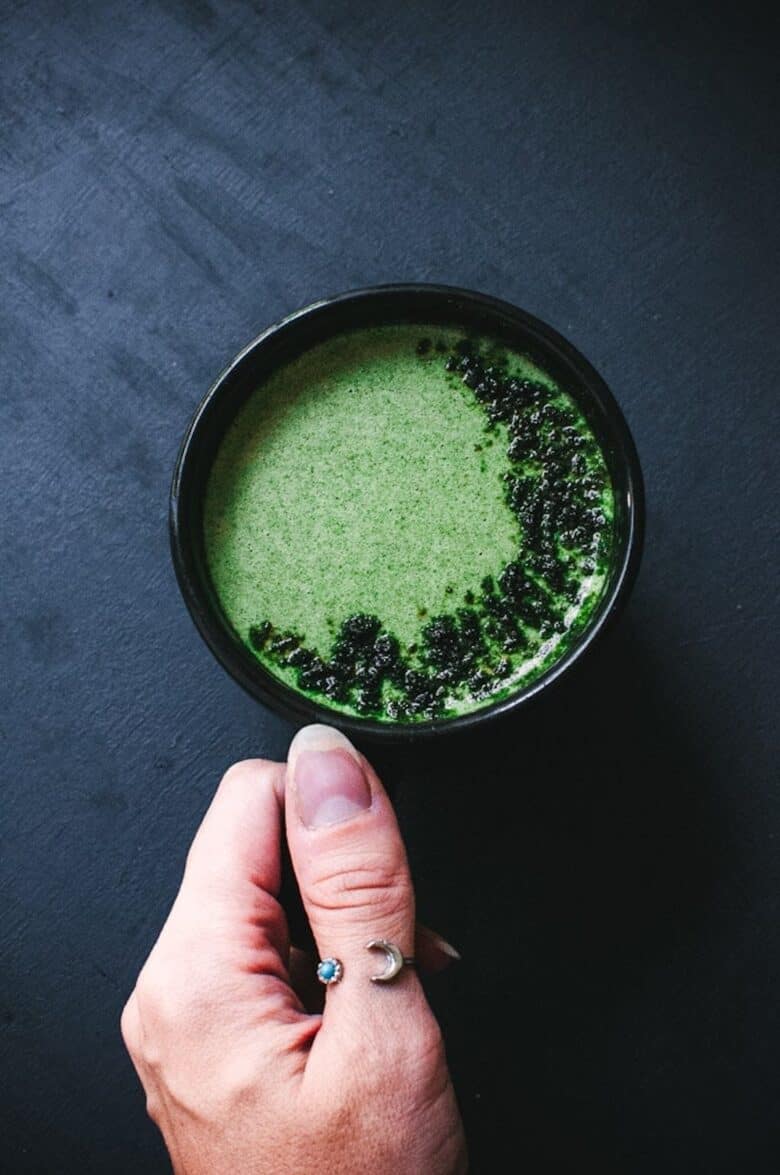 overhead shot of black mug with green moringa latte inside
