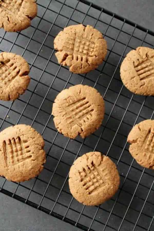 overhead shot of finished gluten-free peanut butter cookies on black wire cooling rack