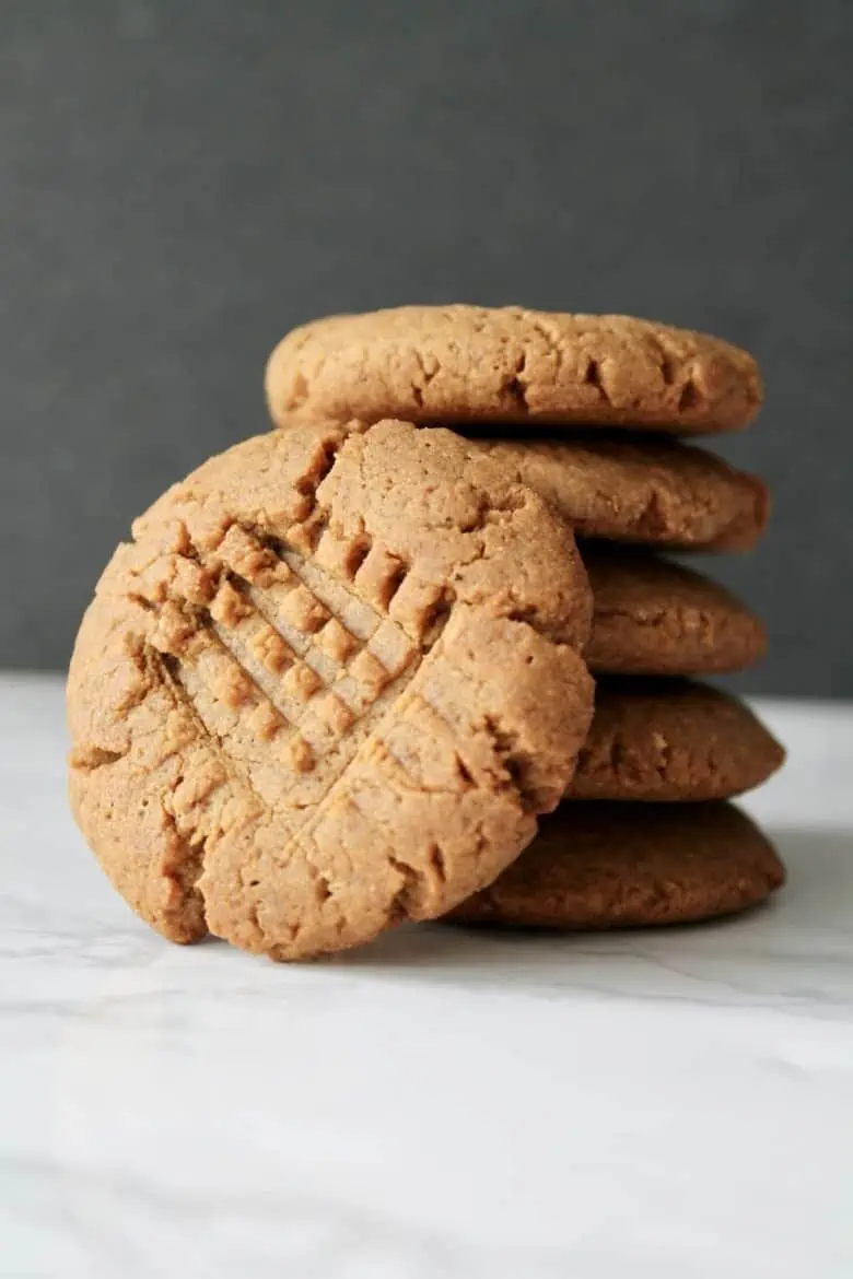 close up of a stack of gluten free peanut butter cookies with one cookie leaning on the stack