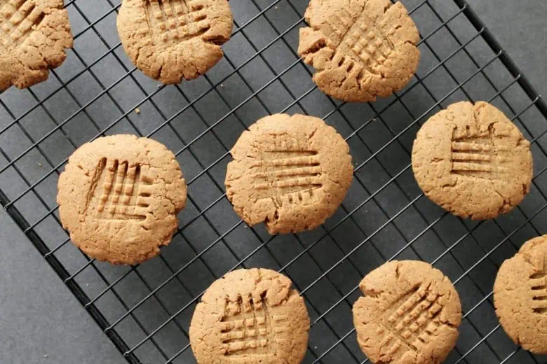 overhead shot of finished gluten-free peanut butter cookies on black wire cooling rack