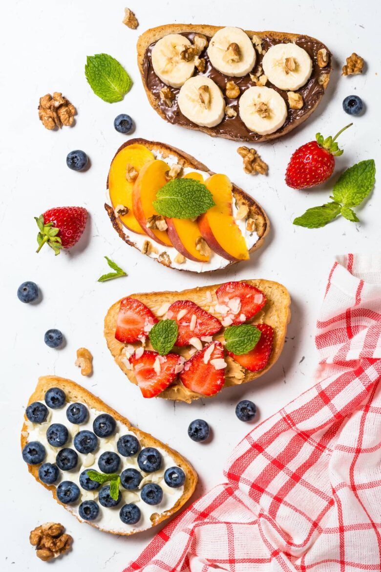 Overhead shot of four pieces of toast with various fruit toppings