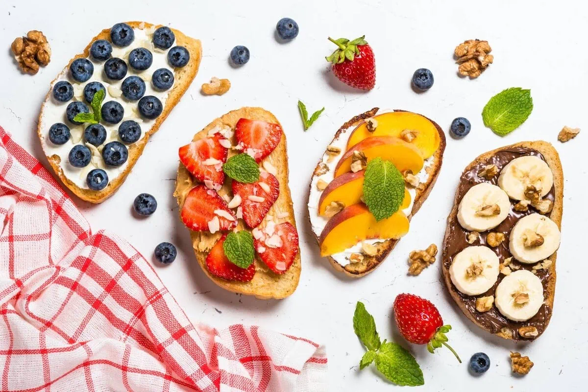 Overhead shot of four pieces of toast with various fruit toppings