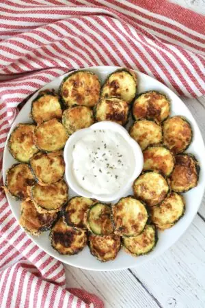 Air Fryer Zucchini chips with dip on a white plate.
