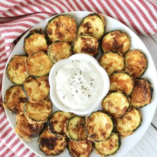 Air Fryer Zucchini chips with dip on a white plate.