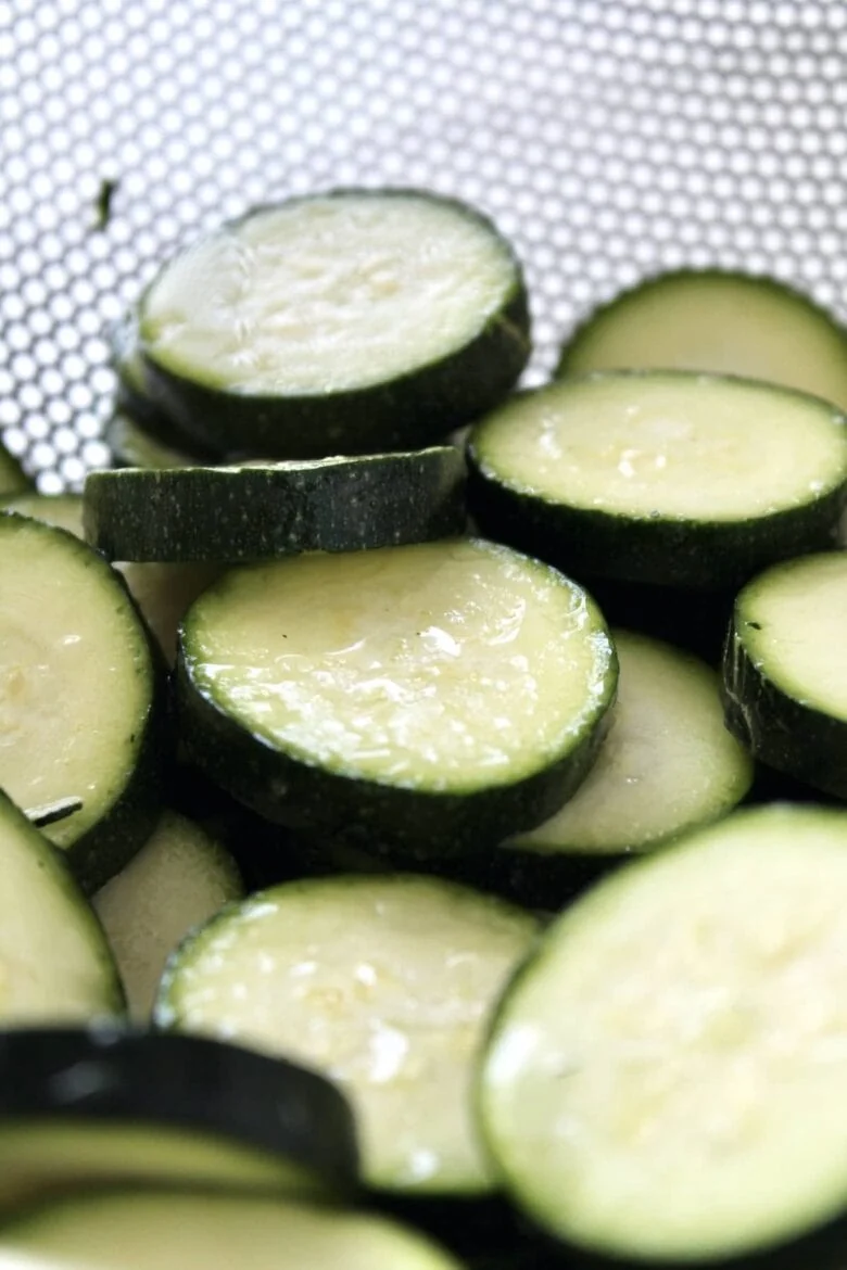 Sliced zucchini strained in a colander.