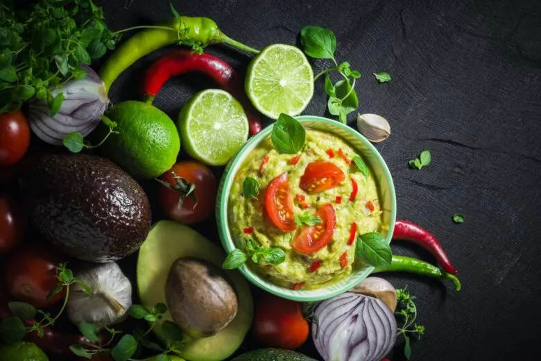 A bowl of guacamole with tomatoes, peppers and other vegetables.