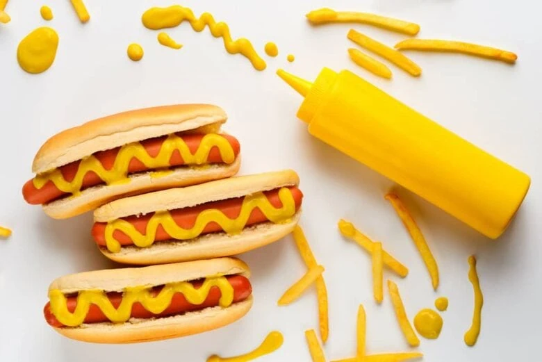 Hot dogs with mustard and french fries on a white background.