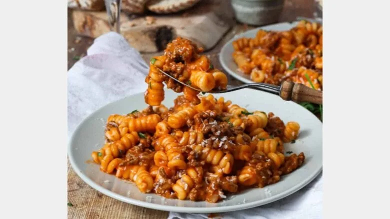 A plate of pasta with meat sauce on it.