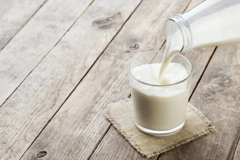 A glass of milk being poured into a glass.