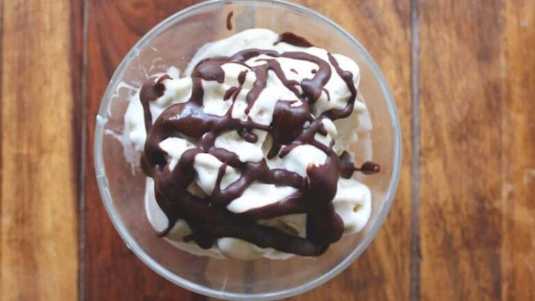 A bowl of ice cream with chocolate sauce on top.