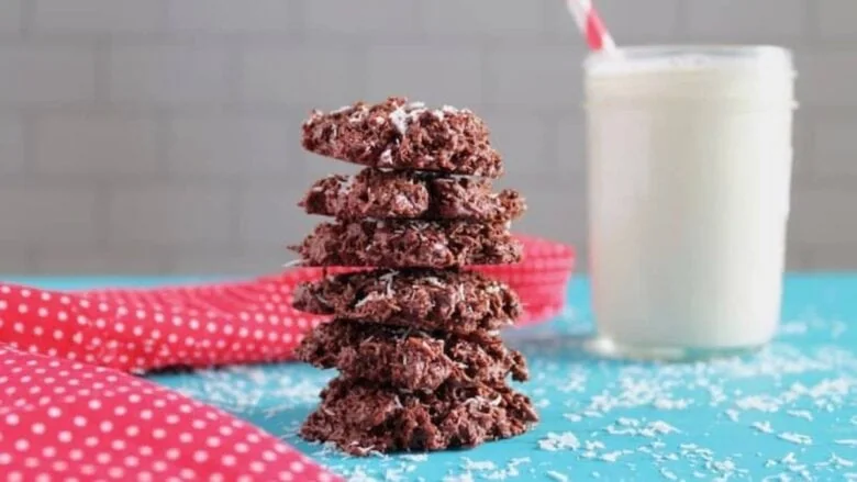 A stack of chocolate no bake cookies next to a glass of milk.