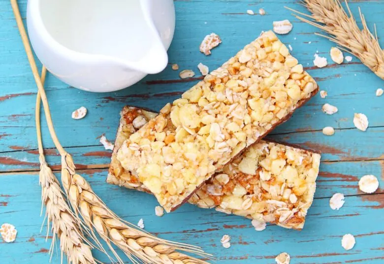 Unhealthy granola bars and a glass of milk on a blue wooden table.
