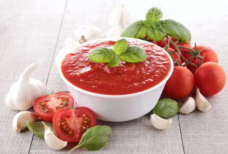Tomato sauce with garlic and basil on a wooden table.
