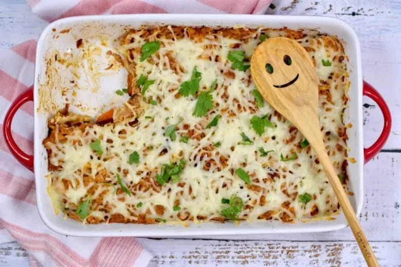 A casserole dish with cheese and a wooden spoon.
