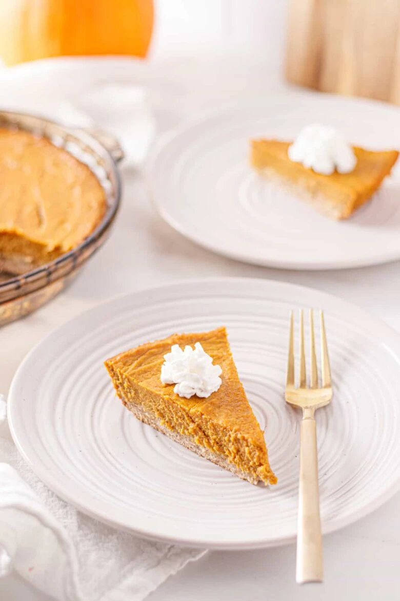 A slice of pumpkin pie on a plate with a fork.