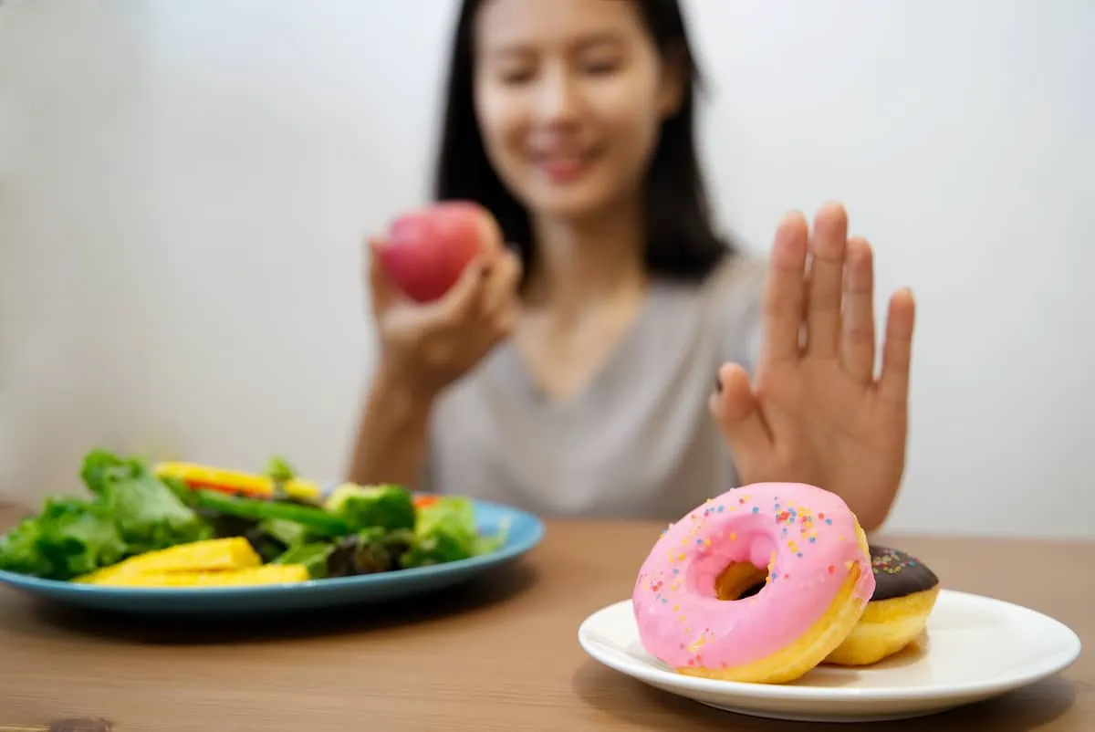 A woman eating an apple in front of a plate.