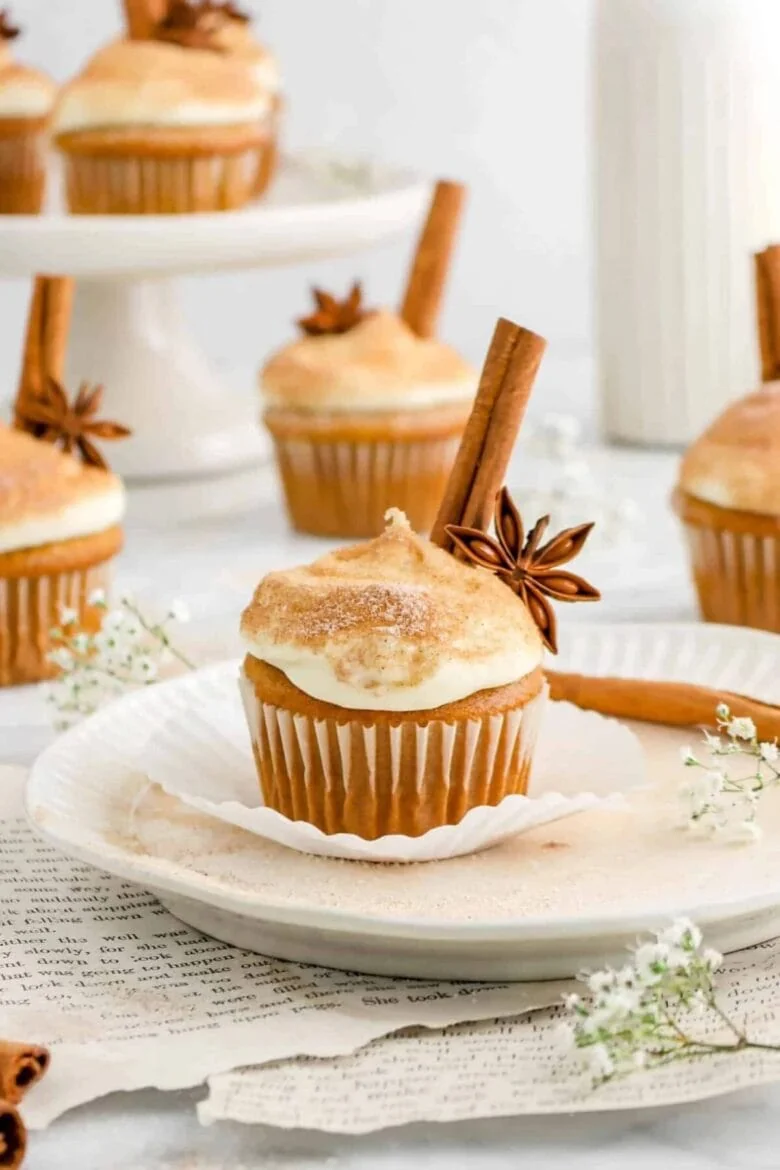 Pumpkin spice cupcakes on a plate with cinnamon sticks.