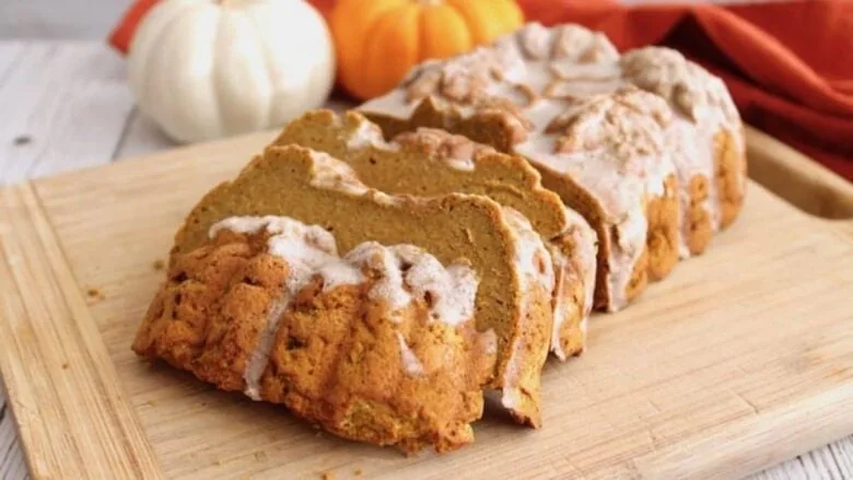 Pumpkin bread with icing on a cutting board.