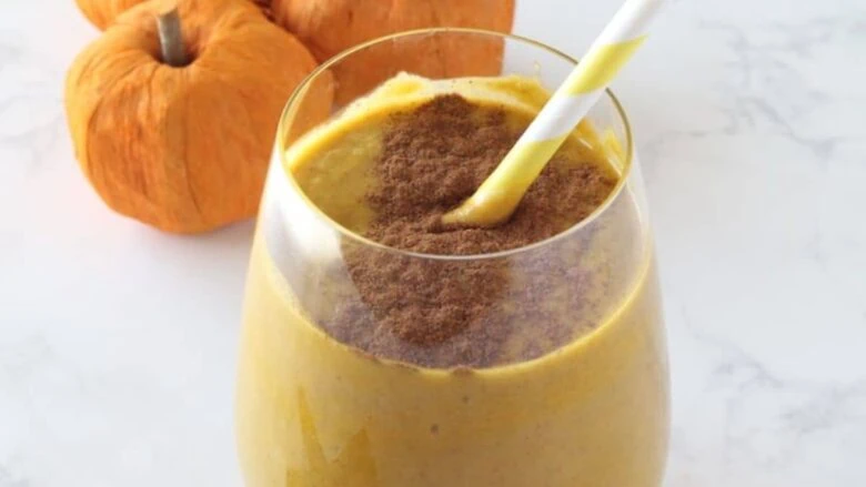 A pumpkin smoothie in a glass with a straw.