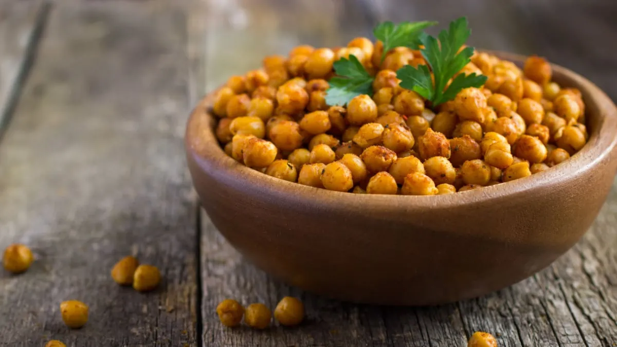 Chickpeas in a wooden bowl on a wooden table, showcasing different types of beans.