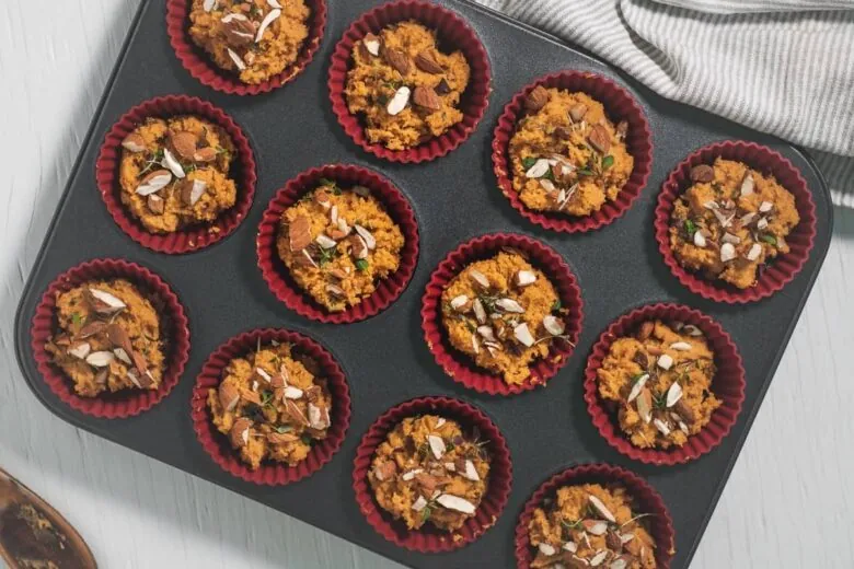 A tray of muffins with almonds in it.