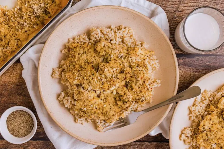 A plate of chicken and rice on a wooden table.