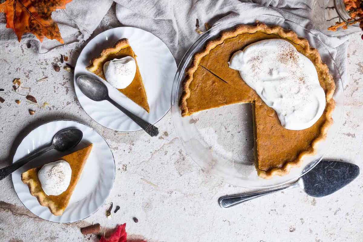 A slice of pumpkin pie with whipped cream on a plate.