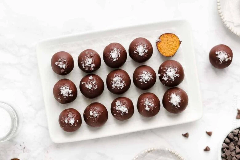 Chocolate covered eggs on a white plate.