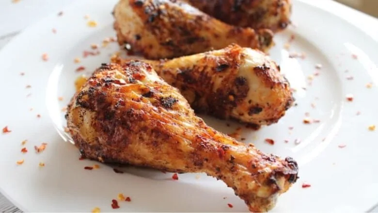 A plate of grilled chicken legs on a white plate.