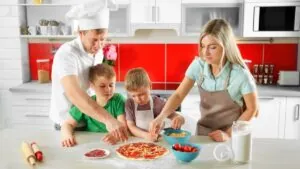 A family is making pizza in the kitchen.
