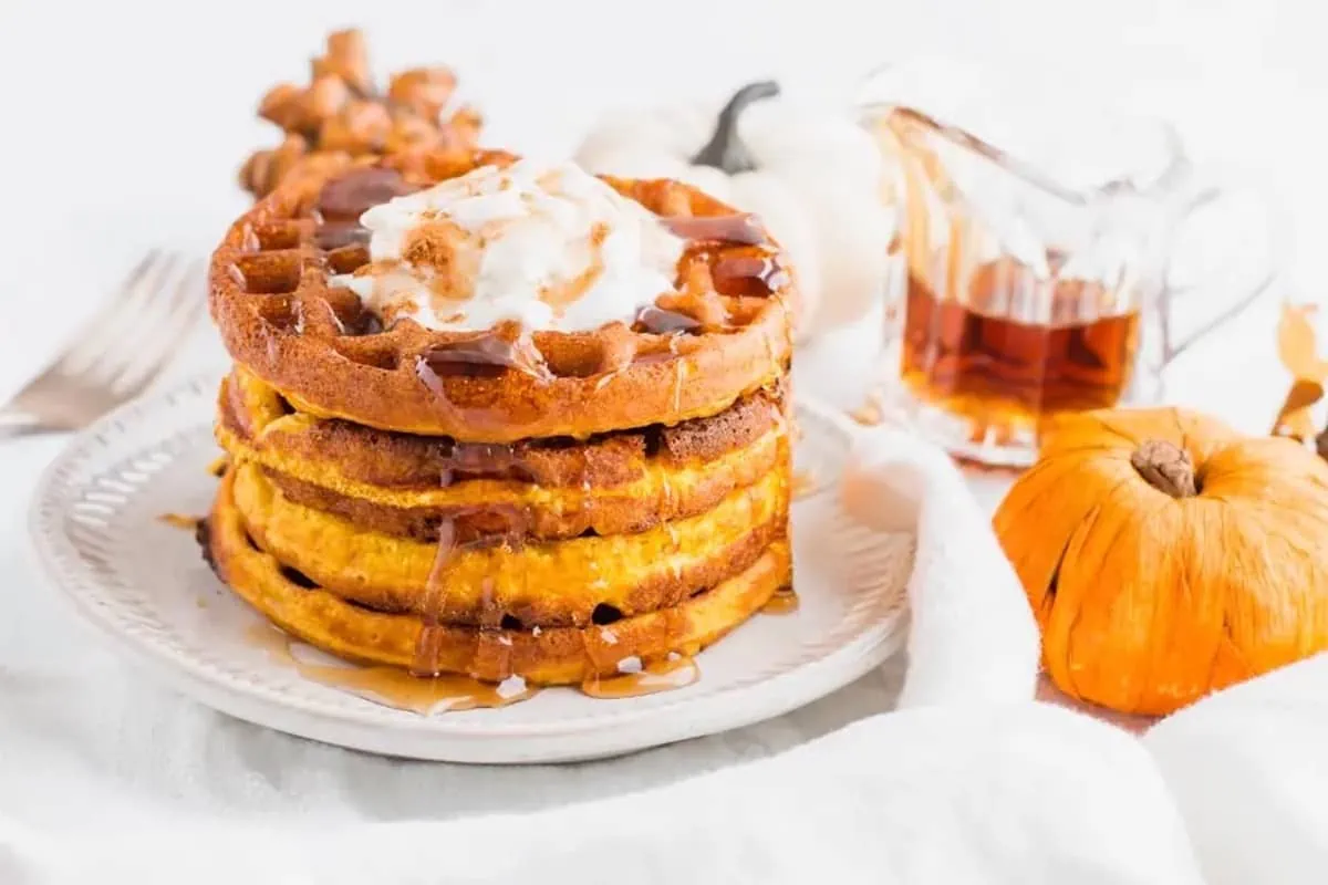 A stack of pumpkin waffles on a white plate.