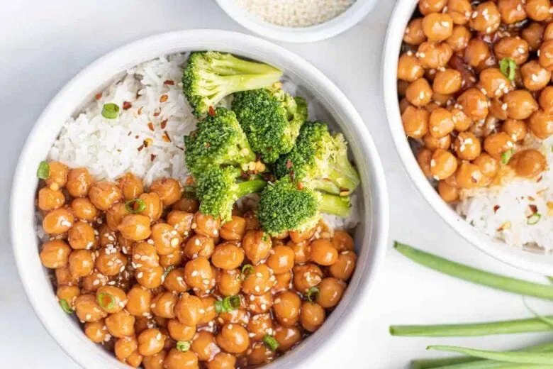 Two bowls of asian chickpeas with rice and broccoli.