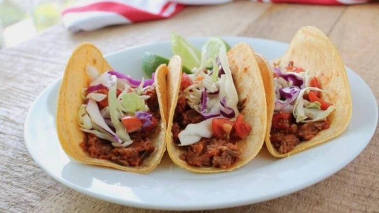 Three tacos on a white plate.