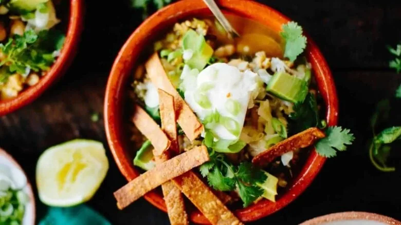 A bowl of mexican soup with tortilla chips and sour cream.