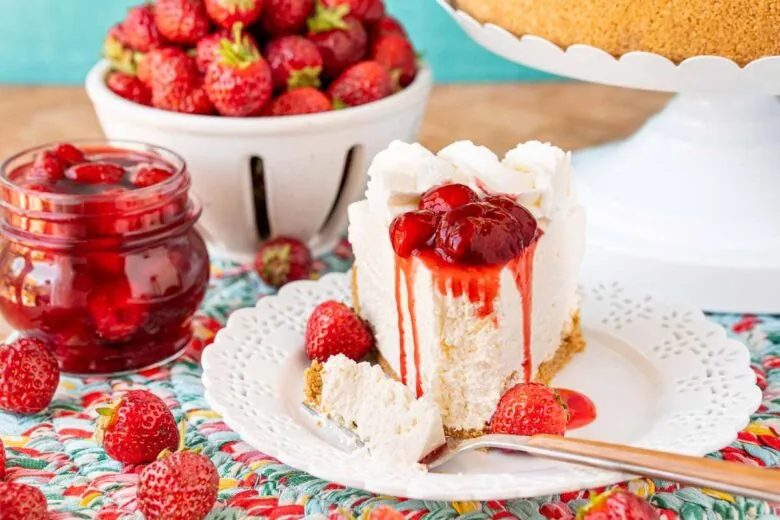 A slice of strawberry cheesecake on a plate with strawberries.