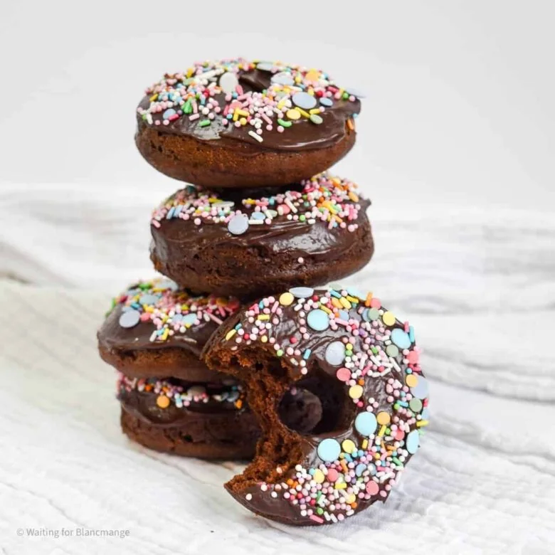 A stack of chocolate donuts with sprinkles on top.