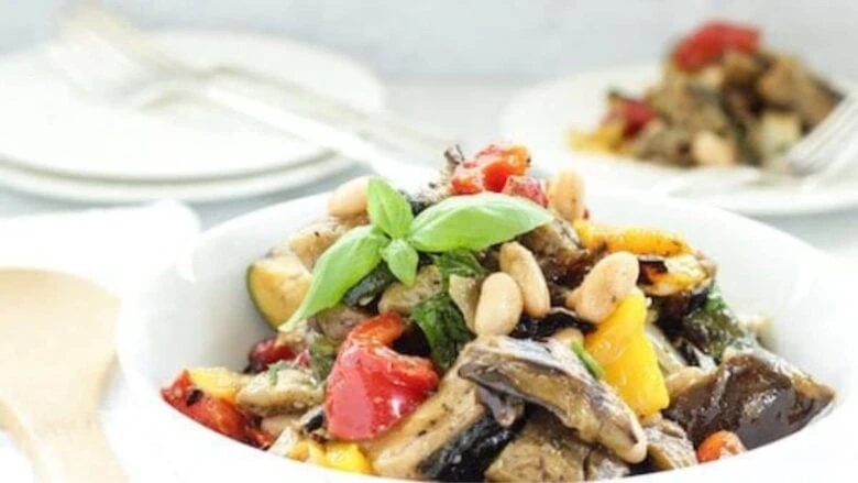 A white bowl filled with vegetables and herbs.