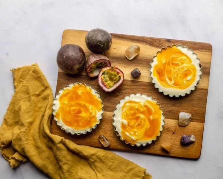 Passion fruit tarts on a wooden cutting board.