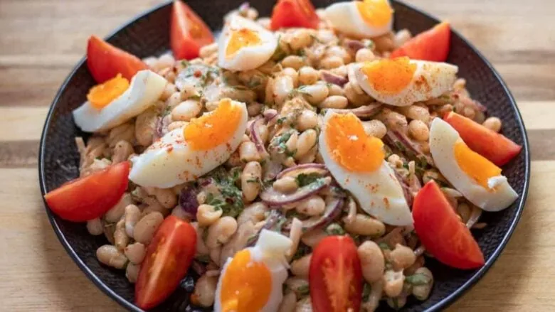 A plate with beans, tomatoes and an egg on top.