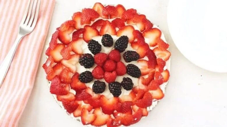 A pie with strawberries and berries on top.