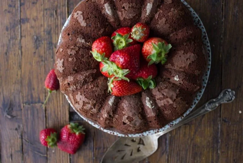 A chocolate bundt cake with strawberries on top.