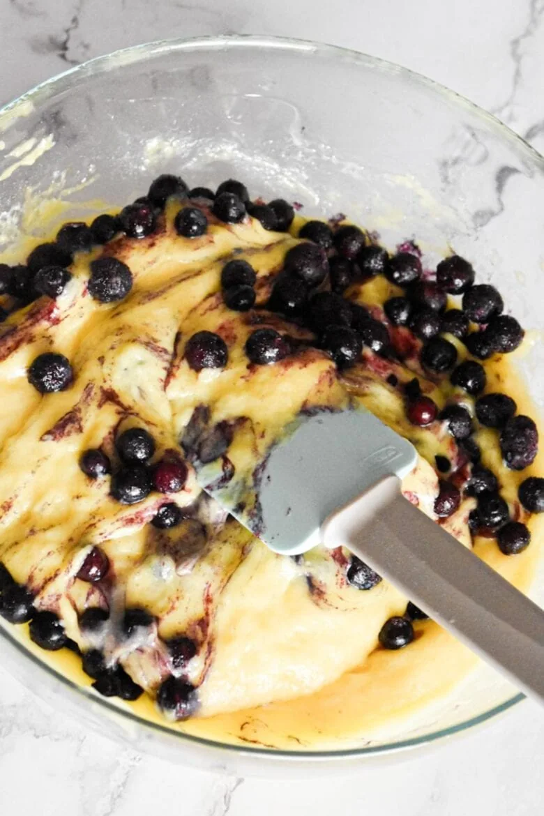 Blueberry pancake batter in a bowl with a spatula, ready to be cooked.