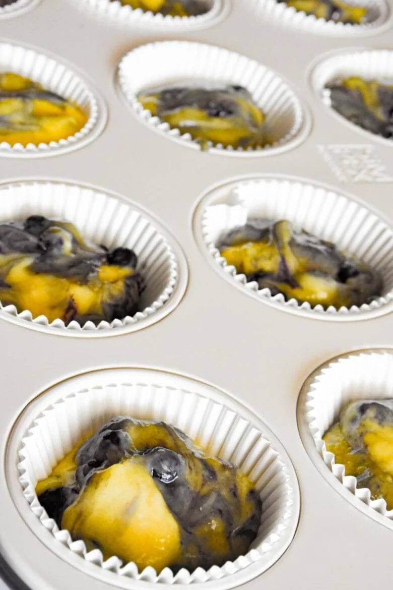 A muffin tin filled with a variety of delicious muffins, including blueberry and cake mix flavors.